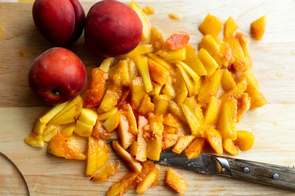 fresh peaches cut on a wooden cutting board